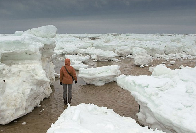 Image of a person in a landscape full of blocks of ice, snow and ice-bergs.