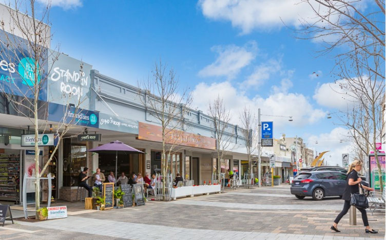 A picture showing trendy shops and cafes in a clean pedestrian mall.